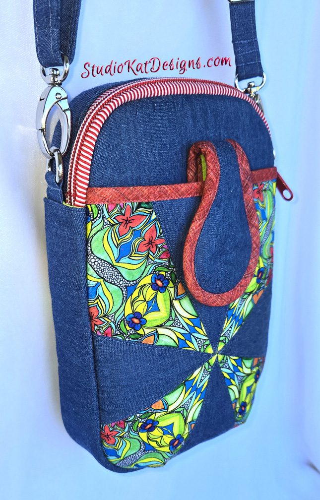 A blue bag with a red handle and some colorful designs