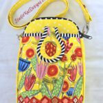 A yellow purse with flowers and stripes on it.