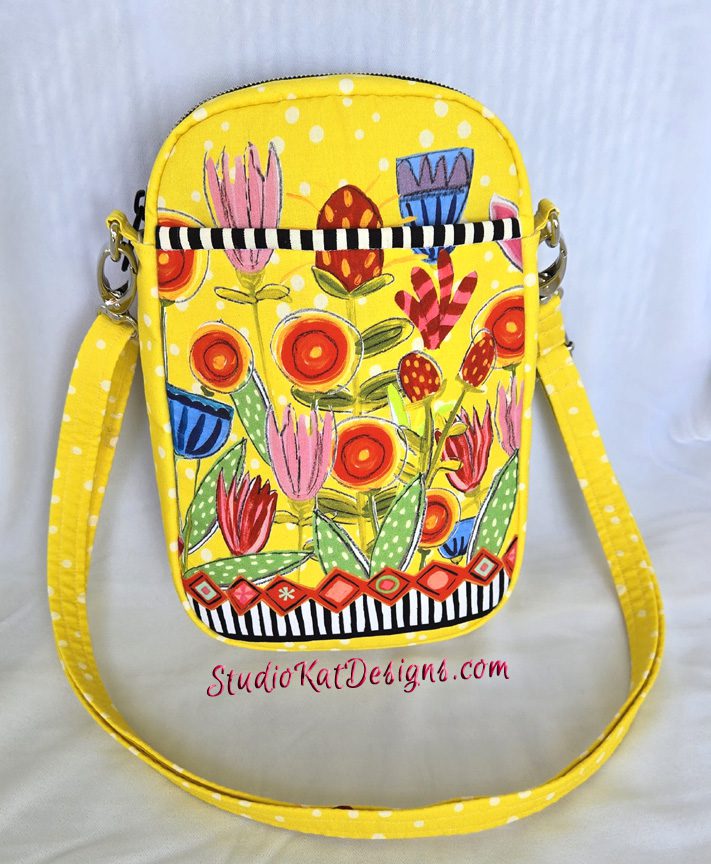 A yellow purse with flowers and stripes on it.