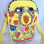 A yellow purse with a black and white striped handle. A yellow purse with a black and white striped handle.