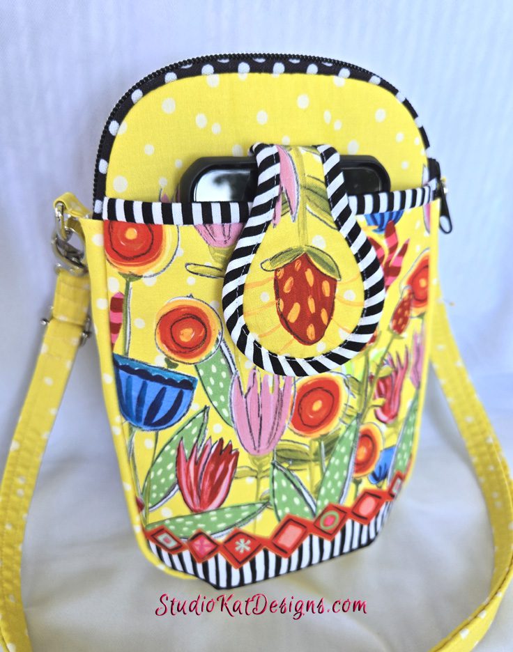 A yellow purse with a black and white striped handle.