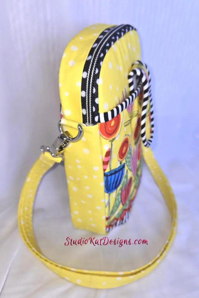 A yellow purse with a black and white polka dot strap.
