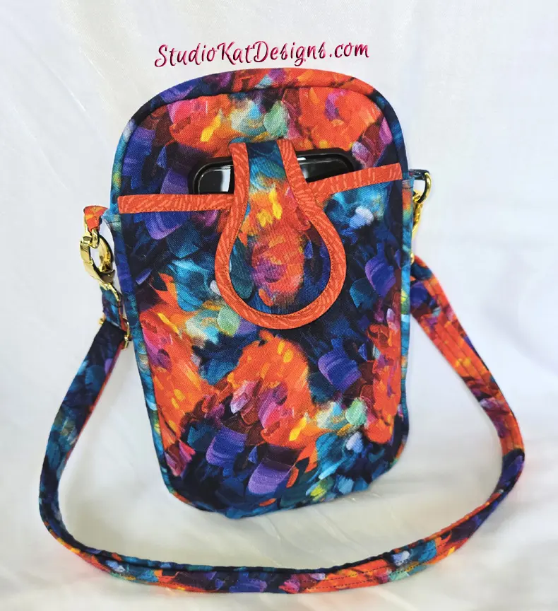 Colorful tie-dye crossbody bag with a leather buckle closure.
