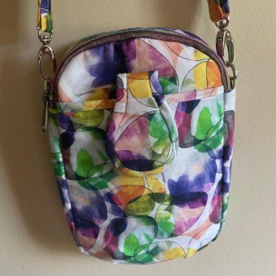 Small colorful crossbody bag with abstract floral design.