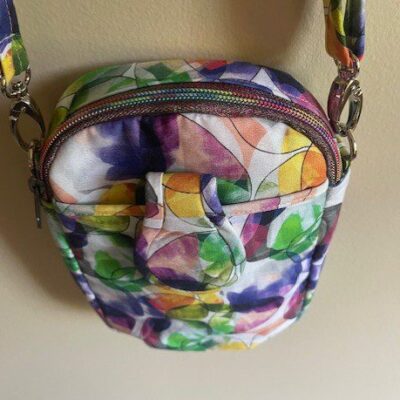 Small colorful floral-patterned crossbody bag with a zipper.