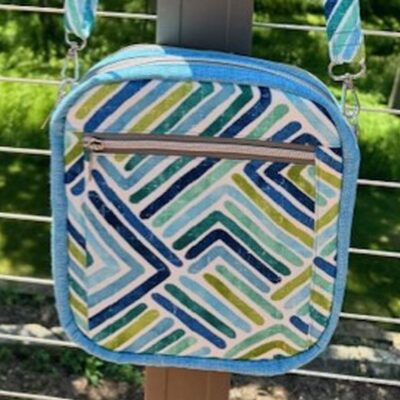 Colorful geometric-patterned bag with a zipper pocket outdoors.