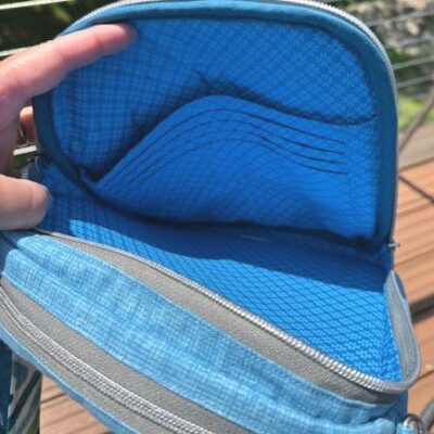 A person holding an open blue wallet with multiple compartments.