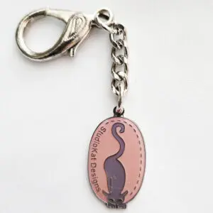 Oval keychain with a black cat silhouette and text.