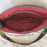 Open colorful handbag with a pink interior lining.