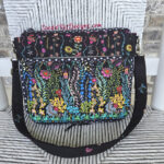Colorful embroidered shoulder bag with floral patterns on black fabric.
