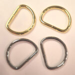 Four metallic D-rings in gold and silver colors on a white surface.