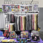 Display rack with colorful backpacks and hanging fabric samples in a store.