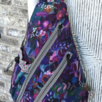 Purple floral patterned sling backpack with zippers