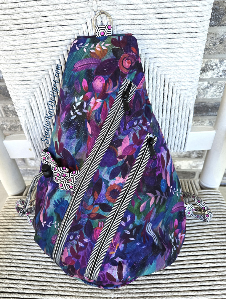 Purple floral sling backpack with diagonal zippers